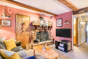 Ein gemütliches Wohnzimmer mit Kamin aus Stein, einem Flachbildfernseher und einer bequemen Couch.