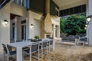 Une terrasse extérieure avec une table à manger, des chaises et un foyer.