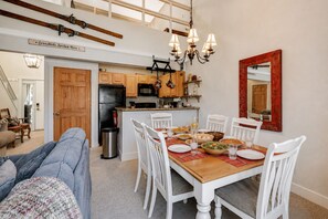Een eetruimte met een houten tafel, witte stoelen en een spiegel met rode lijst.