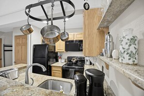 Una cocina moderna con encimeras de granito, electrodomésticos de acero inoxidable y armarios de madera.