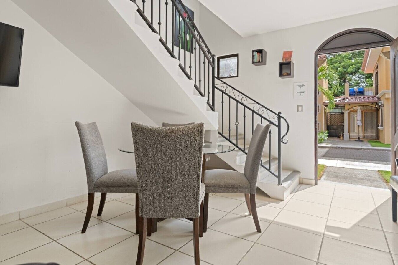 A hotel lobby with a staircase, a dining area with two chairs and a table, and a view of the street outside.