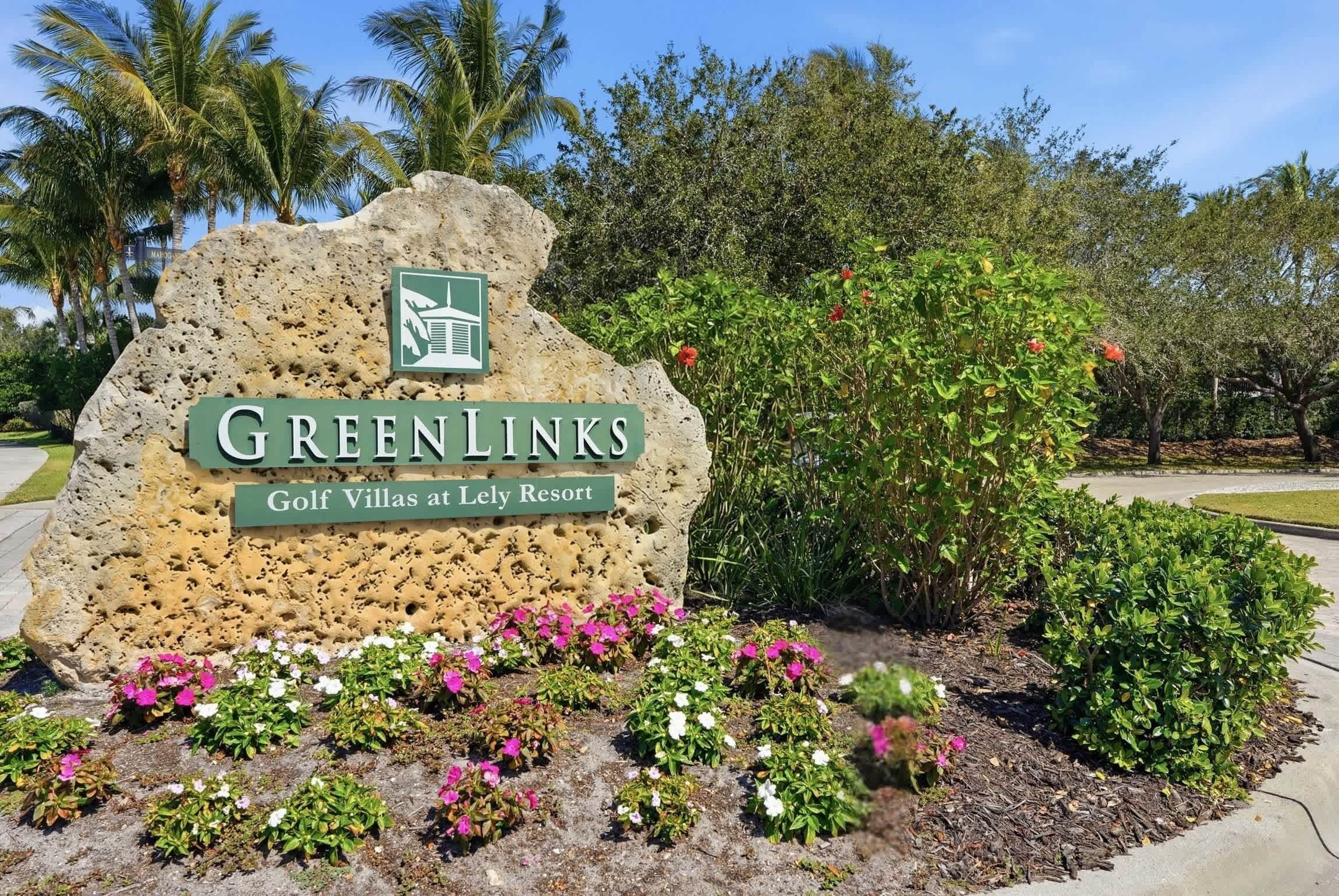 A sign for GreenLinks Golf Villas at Lely Resort with a logo, surrounded by landscaped flowers and greenery.