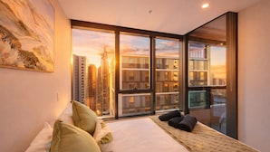 A modern hotel room with a large bed, a view of the cityscape, and a painting on the wall. - 3 Bedroom CBD Apartment with Pool, Gym & Spa with Gorgeous City Views (Melbourne)