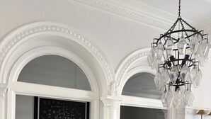 A dining area with a glass table and chairs, a chandelier, and a blackboard with text. - Luxury Downtown Indy • Walk to NCAA Final Four • On American Legion Mall (Indianapolis)