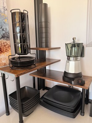 A kitchen with a coffee maker, a blender, and stacked black trays on a wooden countertop. - Beautiful 2-Bedroom modular home in the tranquil country side of Jobos Isabela. (Isabela)