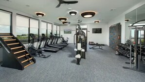 Ein Fitnessstudio mit Laufbändern, Kraftgeräten, einer Klimmzugstange und einer Wand voller Trainingsgeräte.