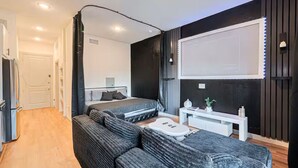 Ein modernes Schlafzimmer mit Bett, Sofa, Schreibtisch und großem Fenster.