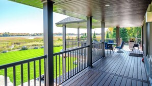 A covered outdoor deck with a view of a grassy field and trees. - Devlok- Mystique Mansion 7 Br-sleep 16 Kawartha (Trent Lakes)