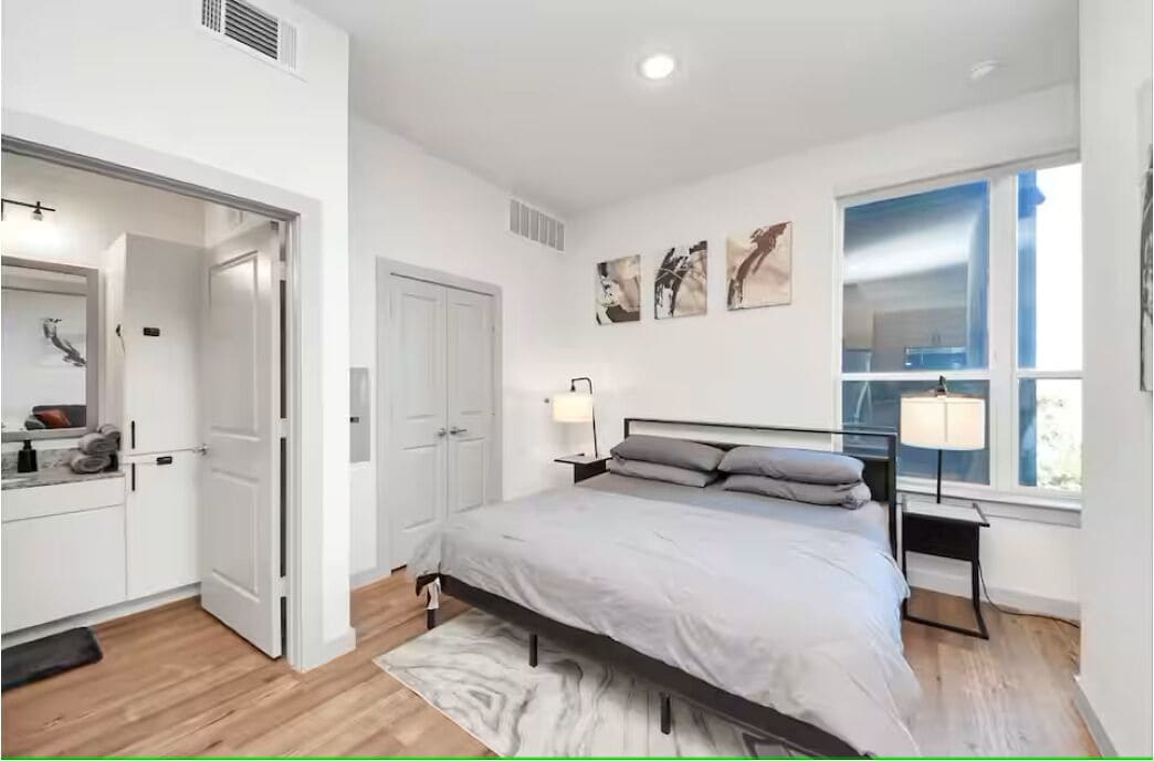 A bedroom with a bed, bedside tables, a window, and a door leading to a bathroom.