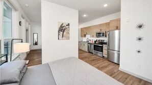 En moderne lejlighed med en seng, et køkken med rustfrie apparater og minimalistisk indretning.