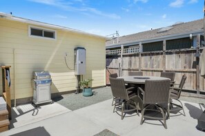 A patio with a table and chairs, a grill, and a utility box.