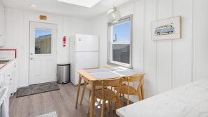 Une cuisine dotée d’une lucarne, d’un réfrigérateur, d’une poubelle et d’une table à manger avec des chaises.