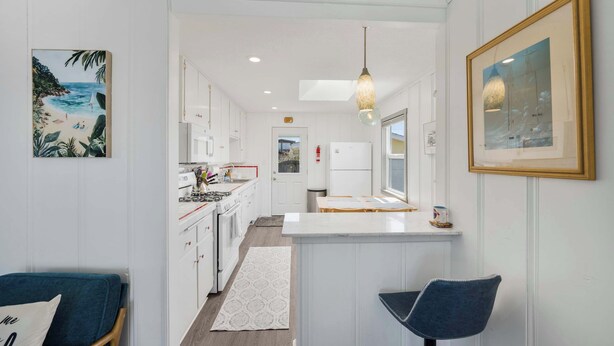Une cuisine moderne avec des meubles blancs, un îlot central et un coin repas équipé de deux chaises.