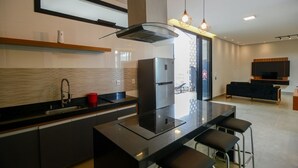 Een moderne keuken met een centraal eiland, roestvrijstalen apparatuur en een zithoek met barkrukken.