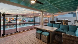Um pátio externo com piscina, área de estar e ventoinha no teto.