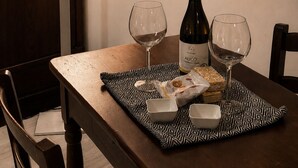 Una mesa de comedor con dos copas de vino, una botella y un mantel individual.