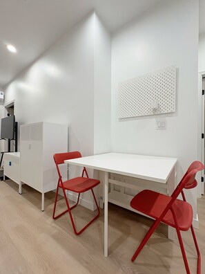 A white room with a white table and red chairs, a whiteboard on the wall, and a whiteboard with a pegboard. - Sunny Cypress Retreat - 1BR + Bonus Bed - New ADU (Cypress)