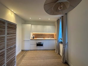 Eine moderne Küche mit weißen Schränken, einer Holz Arbeitsplatte und einem eingebauten Backofen.
