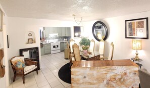 A dining area with a round table, chairs, a fireplace, and a kitchen in the background. - 3-bedroom/ 2 bath fully designer-remodeled house in central Albuquerque, by UNM (Albuquerque)