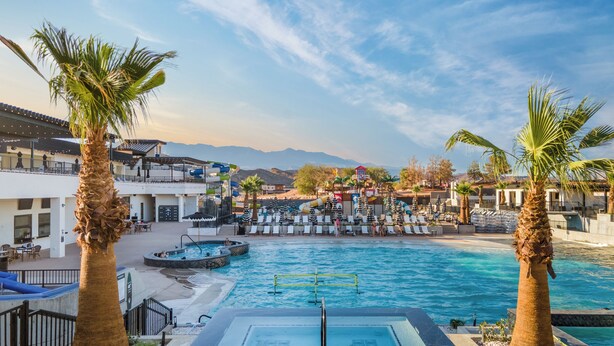 A pool area with lounge chairs, palm trees, and a water slide. - Zion Canyon Mist Resort House (Hurricane)