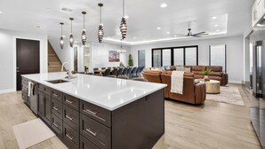 A modern kitchen with a large island, dark cabinetry, and pendant lighting. - Zion Canyon Mist Resort House (Hurricane)
