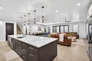 A modern kitchen with a large island, dark cabinetry, and pendant lighting. - Zion Canyon Mist Resort House (Hurricane)