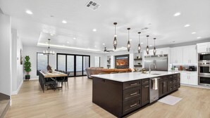 A modern kitchen with a large island, dark cabinetry, and stainless steel appliances. - Zion Canyon Mist Resort House (Hurricane)