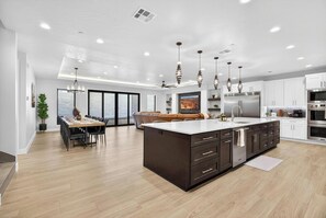 A modern kitchen with a large island, dark cabinetry, and stainless steel appliances. - Zion Canyon Mist Resort House (Hurricane)