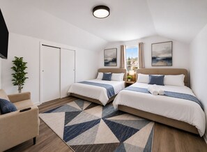 Une chambre d’hôtel avec deux lits, un canapé, une télévision et une grande fenêtre avec des rideaux.