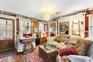 A cozy living room with a wooden table, a sofa, a patterned rug, and a chandelier.