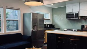 A modern kitchen with a refrigerator, microwave, and stove. There is a bar stool and a small round table with a tray. - Boutique 1BR Private Unit with AC, Silicon Valley, 5 min Santana Row, fast WiFi (San Jose)