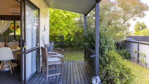 A covered outdoor area with a wooden deck, a table with chairs, and a peacock statue. - Family-Friendly 3BR Home Close to Lake Taupō (Taupō)