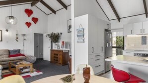 A modern kitchen with white cabinets, a stainless steel refrigerator, and a red chair. - Family-Friendly 3BR Home Close to Lake Taupō (Taupō)