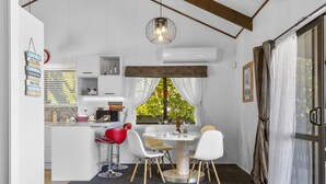 A compact kitchen with a dining area, a built-in air conditioner, and a view of greenery outside. - Family-Friendly 3BR Home Close to Lake Taupō (Taupō)