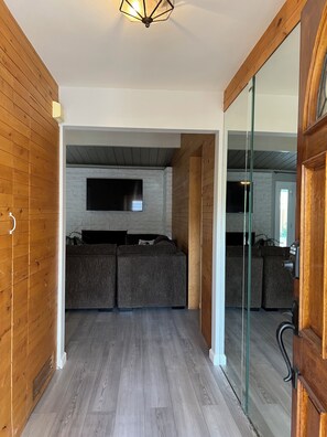 A modern interior with a stone fireplace, a flat-screen TV, and a wooden floor. - 2-bedroom house in charming Rancho Mirage with AC (Rancho Mirage)