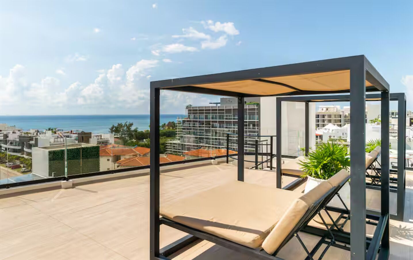 Une terrasse sur le toit avec un transat, une pergola et une vue sur la ville et l’océan.