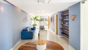 Ein moderner Flur mit einem blauen Sofa, einem weißen Couchtisch mit getrockneten Blumen und einer Treppe, die in eine obere Etage führt.