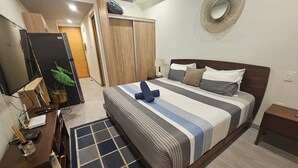 Ein Hotelzimmer mit einem Bett, einem Schreibtisch mit Computer, einem Fernseher und einer Zimmerpflanze.