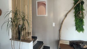 A staircase with a wooden railing, a potted plant, and a wall-mounted light fixture. - Villa Sainte Anne whole house and Spa overlooking the Alpilles (Sénas)