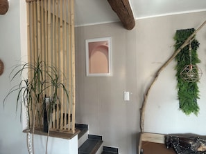Een trap met houten leuning, een bloempot en een wandlamp.