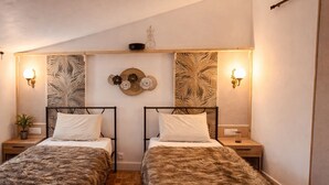 A room with two beds, each with a headboard, a wall-mounted shelf with decorative items, and wall sconces. - Villa Sainte Anne whole house and Spa overlooking the Alpilles (Sénas)