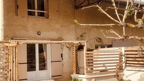 A rustic building with wooden shutters, a covered entrance, and a stone wall. - Villa Sainte Anne whole house and Spa overlooking the Alpilles (Sénas)