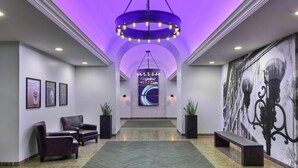 A hotel lobby with a modern design, featuring a central chandelier, seating area with chairs and a bench, a large wall mural, and a digital display screen. - Sleek City-View King Suite Near San Diego’s Best Food & Nightlife (San Diego)