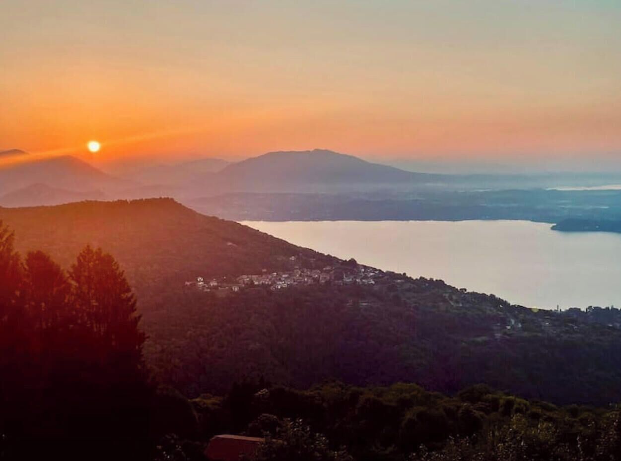Un paisaje montañoso con una masa de agua y un pequeño asentamiento.