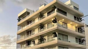 Een meerlaags gebouw met balkons, ramen en een heldere lucht.