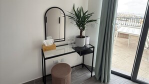 A modern room with a desk, a potted plant, a mirror, and a view of an outdoor patio. - Doni Signature Penthouse with HotTub and Sea Views (Il-Mellieħa)