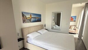A bedroom with a bed, a bedside table, a mirror, and a painting on the wall. - Doni Signature Penthouse with HotTub and Sea Views (Il-Mellieħa)