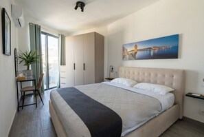 A bedroom with a bed, a desk, a chair, a potted plant, and a painting on the wall. - Doni Signature Penthouse with HotTub and Sea Views (Il-Mellieħa)