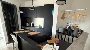 A modern kitchen with a central island, black cabinetry, and hanging wooden signs. - Doni Signature Penthouse with HotTub and Sea Views (Il-Mellieħa)