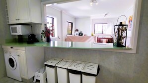 Eine Küche mit Waschmaschine, Mikrowelle und Mülleimern zur Mülltrennung.